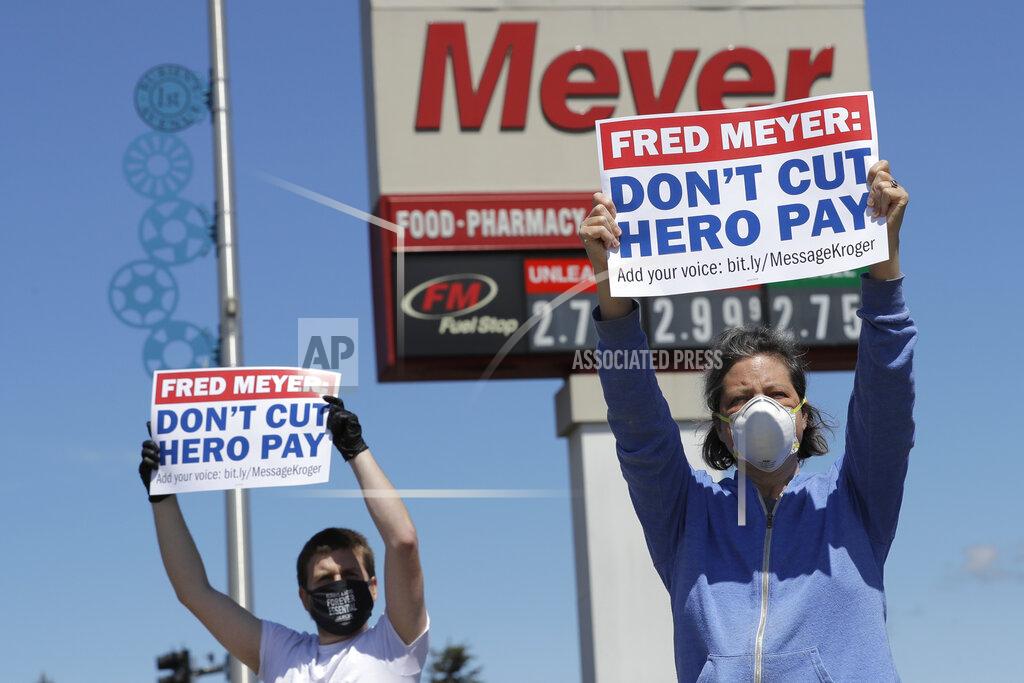 Ted S. Warren Heather Day, right, takes part in a protest outside the Fred Meyer grocery store in Burien, Wash., against Fred Meyer's parent company Kroger, Friday, May 15, 2020, that was organized by the United Food and Commercial Workers International Union. Kroger officials have said they are ending the additional $2 hourly "hero pay" bonus that had been paid to workers since late March during the coronavirus pandemic. The company said Friday it will now offer one-time bonus payments of $400 and $200 for full- and part-time employees to be paid in two installments. (AP Photo/Ted S. Warren)