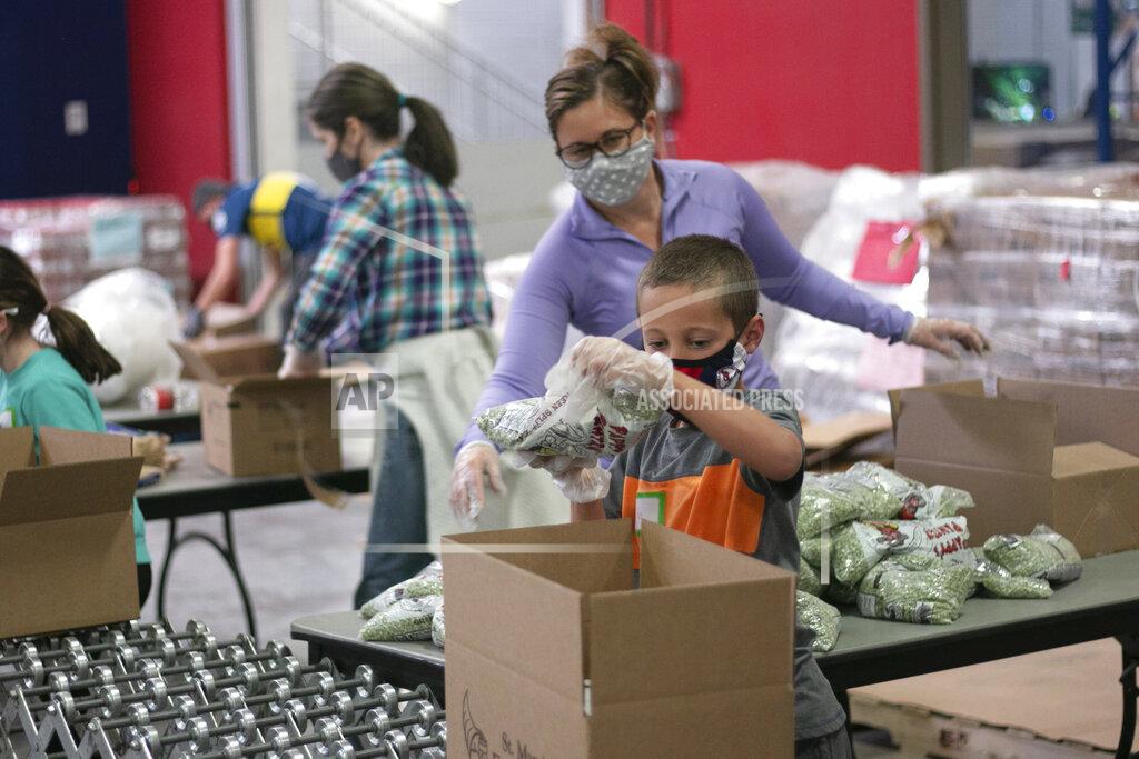 Cheyanne Mumphrey Phoenix resident Erin Pfeifer, 40, unloads boxes of bagged peas as her 8-year-old son, Dylan, places them into the boxes at St. Mary's Food Bank in Phoenix on Thursday, March 18, 2021. This was the second volunteer event Pfeifer and her son attended with the food bank. (AP Photo/Cheyanne Mumphrey)
