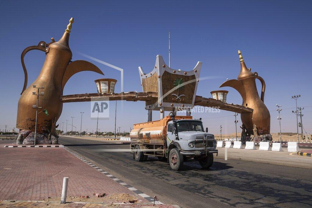 Bernat Armangue In this Monday, Jan. 13, 2020 photo, a track drives past the entrance gate of Wadi Al Dawasir, Saudi Arabia. Formerly known as the Paris-Dakar Rally, the race was created by Thierry Sabine after he got lost in the Libyan desert in 1977. Until 2008, the rallies raced across Africa, but threats in Mauritania led organizers to cancel that year's event and move it to South America. It has now shifted to Saudi Arabia. The race started on Jan. 5 with 560 drivers and co-drivers, some on motorbikes, others in cars or in trucks. Only 41 are taking part in the Original category. (AP Photo/Bernat Armangue)