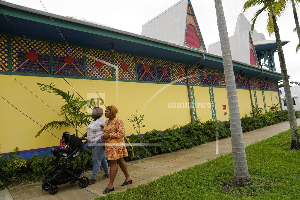 Rebecca Blackwell Krystina Francois, right, and Francesca Menes, children of Haitian immigrants to the U.S. and co-founders of the Black Collective, walk past the Mache Ayisyen, or Haitian Market, Tuesday, Sept. 21, 2021, in Miami. Menes and Francois, whose advocacy organization focuses on the political needs and economic empowerment of Black people across the African diaspora, have called for the Biden administration to immediately suspend plans to remove migrants via planes bound for Haiti. (AP Photo/Rebecca Blackwell)
