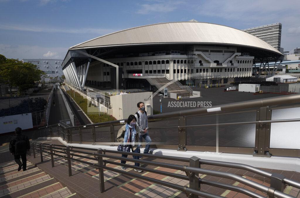 Hiro Komae People walk past Ariake Colosseum, a venue planned to be used for the postponed Tokyo 2020 Olympic and Paralympic Games, in Tokyo Thursday, April 8, 2021. Many preparations are still up in the air as organizers try to figure out how to hold the postponed games in the middle of a pandemic. (AP Photo/Hiro Komae)
