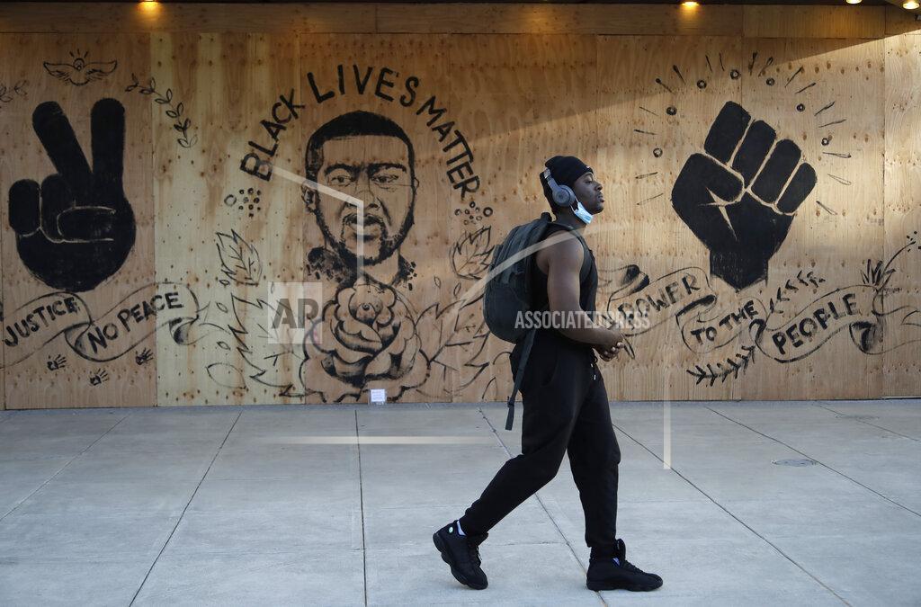Ben Margot A man walks past graffiti spray-painted on a boarded-up theater Tuesday, June 2, 2020, in Redwood City, Calif. (AP Photo/Ben Margot)