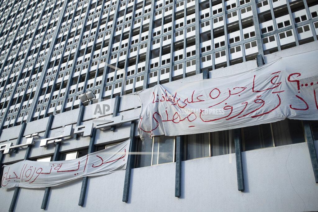 Mosa'ab Elshamy Banners are hung on a building in Tunis' landmark Avenue Habib Bourgiba, where massive protests took place in 2011, on the tenth anniversary of the uprising , in Tunis, Thursday, Jan. 14, 2021. Banners read "The uprising of the poor begins" Tunisia is commemorating the 10th anniversary since the flight into exile of its iron-fisted leader, Zine El Abidine Ben Ali, pushed from power in a popular revolt that foreshadowed the so-called Arab Spring. But there will be no festive celebrations Thursday marking the revolution in this North African nation, ordered into lockdown to contain the coronavirus. (AP Photo/Mosa'ab Elshamy)