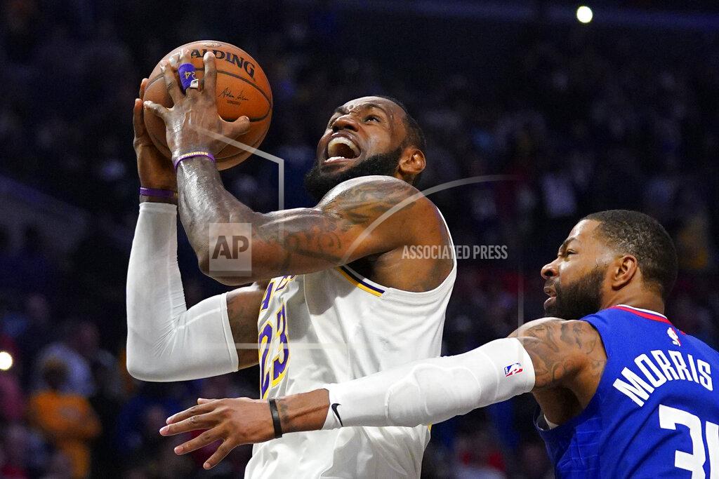 Mark J. Terrill FILE - In this March 8, 2020, file photo, Los Angeles Lakers forward LeBron James, left, shoots as Los Angeles Clippers forward Marcus Morris Sr. defends during the second half of an NBA basketball game in Los Angeles. The NBA is a few weeks from playoff mode, and James has himself and the Lakers squarely in the mix to compete for championship. It is a rare bit of normalcy for a player who appeared in eight consecutive NBA Finals from 2011 through and including 2018, and for a franchise that has won 16 championships. (AP Photo/Mark J. Terrill, File)