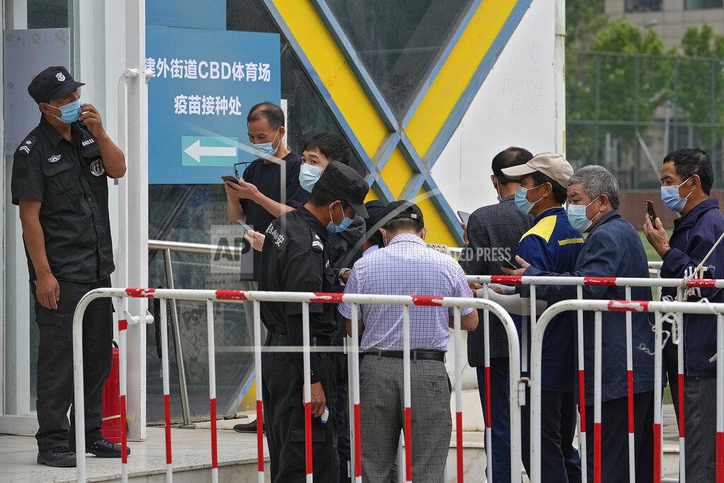 Andy Wong Security guards help masked residents to scan their health code as they line up to receive the Sinopharm COVID-19 vaccine at a vaccination center in the Central Business District in Beijing, Wednesday, June 2, 2021. After a slow start, China is now doing what virtually no other country in the world can: harnessing the power and all-encompassing reach of its one-party system and a maturing domestic vaccine industry to administer shots at a staggering pace. (AP Photo/Andy Wong)