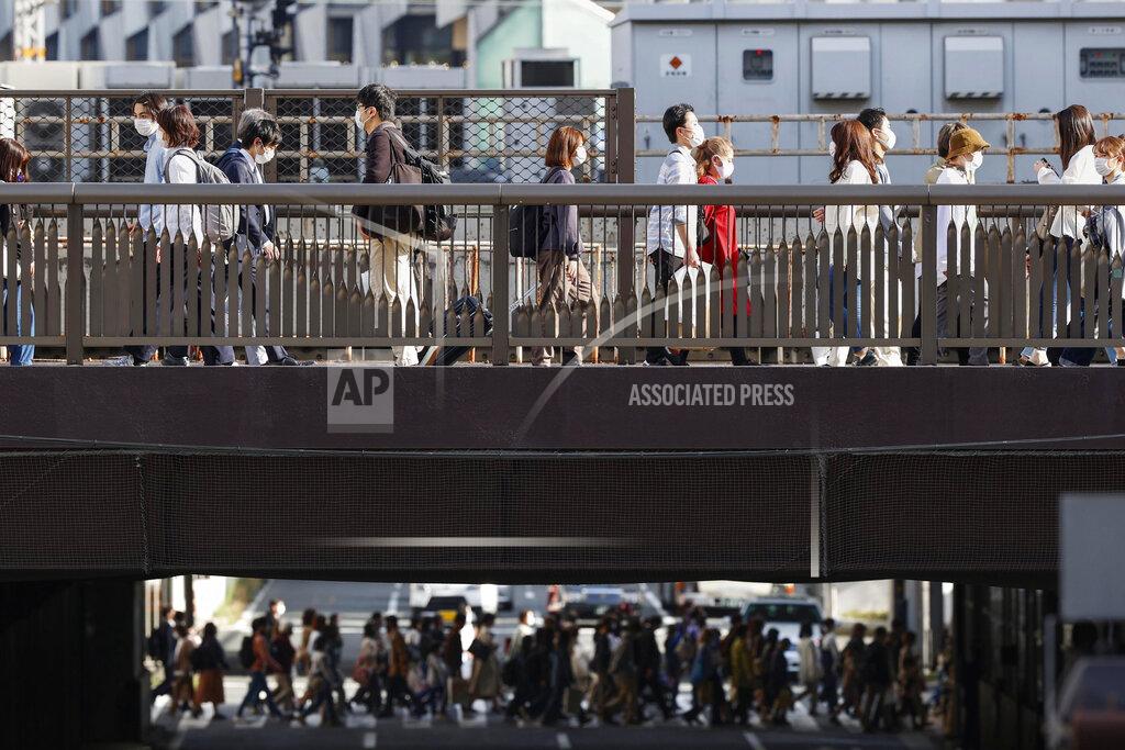 People wear face masks as they make their way in Osaka, western Japan Wednesday, March 31, 2021. Japan is set to designate Osaka and two other prefectures for new virus control steps Thursday as infections in those areas rise less than four months before the Tokyo Olympics. (Kyodo News via AP)