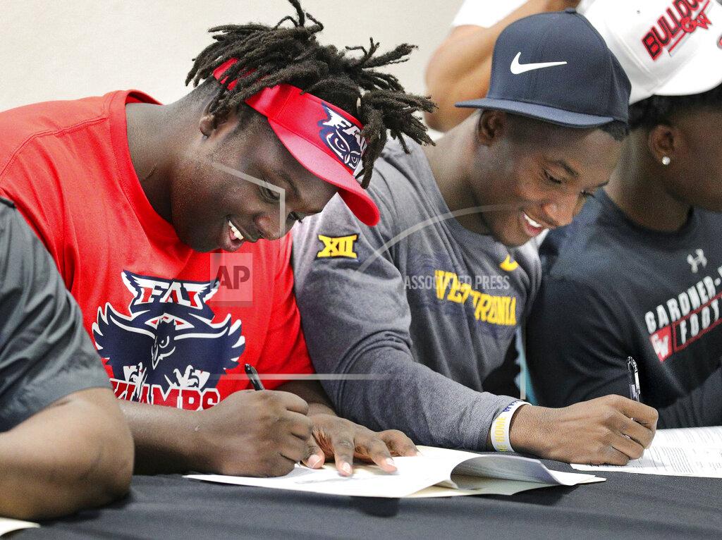 Joe Burbank Evan Anderson, left, committing to Florida Atlantic University, and Avarius Sparrow, committing to West Virginia, sign their commitment papers during a National Signing Day ceremony at Jones High School, Wednesday, Feb. 5, 2020, in Orlando, Fla. (Joe Burbank