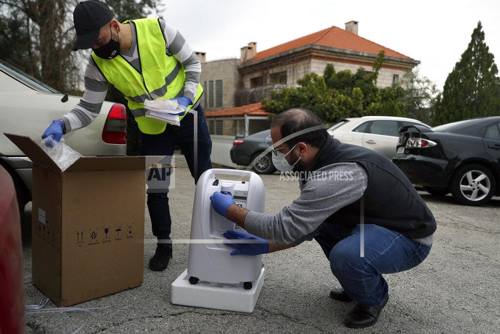 Members of Lebanese NGO Baytna Baytak Firas Minnawi, right, and Mario Suleiman, left, unpack oxygen machine to be donated to an elderly COVID-19 patient in Beit Shebab, a mountain village 15 mile (24 km) north of Beirut, Lebanon, Wednesday, Jan. 27, 2021. The group of Lebanese activists are matching empty apartments and hotel rooms with nurses and doctors who are serving countless hours in the country's hospitals overwhelmed with COVID patients and who need a place to rest without endangering their families or elderly parents. (AP Photo/Bilal Hussein)
