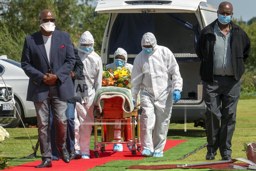 Jerome Delay Pallbearers wearing full PPE suits lift the casket containing the remains of Benedict Somi Vilakasi for his burial ceremony at the Nasrec Memorial Park outside Johannesburg Thursday, April 16, 2020. Vilakasi, a Soweto coffee shop manager, died of Covid-19 infection in a Johannesburg hospital Sunday April 12 2020. South Africa is under a strict five-week lockdown in a effort to fight the Coronavirus pandemic.(AP Photo/Jerome Delay)