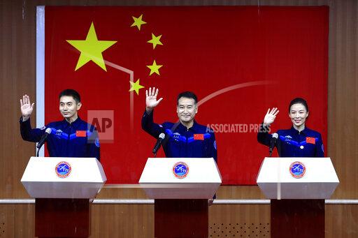 In this photo released by Xinhua News Agency, Chinese astronauts, from left, Ye Guangfu, Zhai Zhigang and Wang Yaping wave to reporters as they arrive for a press conference at the Jiuquan Satellite Launch Center ahead of the Shenzhou-13 launch mission from Jiuquan in northwestern China, Thursday, Oct. 14, 2021. China is preparing to send three astronauts to live on its space station for six months — a new milestone for a program that has advanced rapidly in recent years. (Ju Zhenhua/Xinhua via AP)