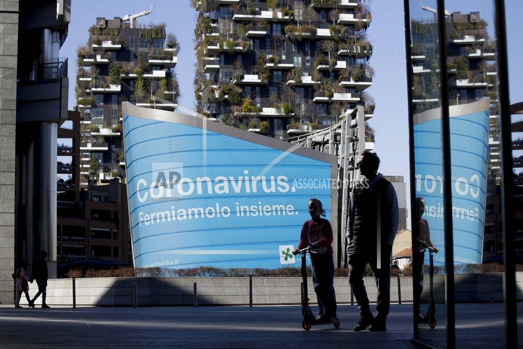 Luca Bruno FILE - In this March 11, 2020, file photo, a man and a girl on a scooter are backdropped by a Lombardy region campaign advertising reading in Italian ' Coronavirus let's stop it together ', at the Porta Nuova business district in Milan. Italy closed shops and restaurants after locking down in the face of 10,000 reported infections. (AP Photo/Luca Bruno, File)