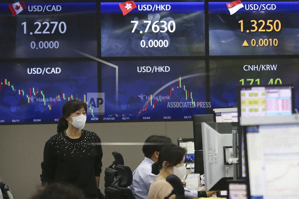 Ahn Young-Joon A currency trader passes by screens showing foreign exchange rates at the foreign exchange dealing room of the KEB Hana Bank headquarters in Seoul, South Korea, Friday, April 30, 2021. Asian shares were mostly lower Friday amid uncertainty about the prospects for a gradual global economic recovery from the coronavirus pandemic. (AP Photo/Ahn Young-joon)