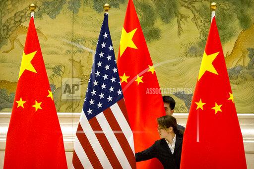 FILE - In this Feb. 14, 2019 file photo, Chinese staffers adjust U.S. and Chinese flags before the opening session of trade negotiations between U.S. and Chinese trade representatives at the Diaoyutai State Guesthouse in Beijing. For nine months under President Joe Biden, the U.S. has engaged in a diplomatic dynamic that could be characterized as about China, without China. On security, trade, climate and COVID-19, the Biden White House has tried to reorient the focus of the U.S. and its allies toward the strategic challenges posed by a rising China — all while there has been little direct engagement between the two rivals. The president is now preparing for a pair of global summits where he again won't be meeting with China’s Xi Jinping but the tensions and aggravations between the world's two largest economies will nonetheless be on ready display.(AP Photo/Mark Schiefelbein, Pool)