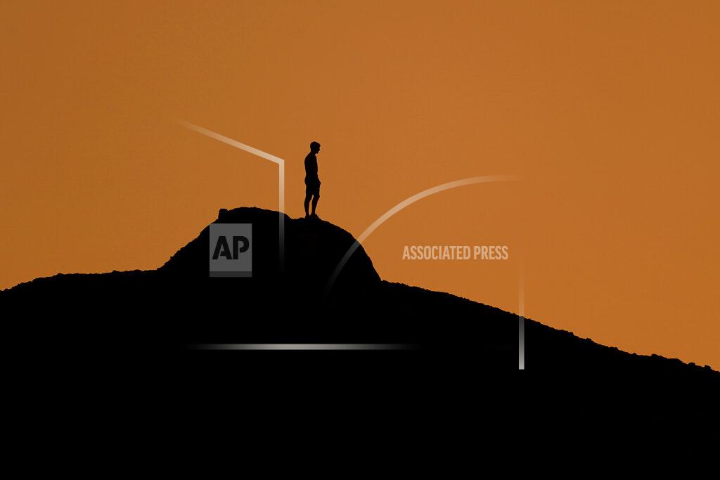 Charlie Riedel FILE - In this Feb. 19, 2021, file photo a man watches the sunset from a peak at Papago Park in Phoenix. Millions of Americans are struggling through life with few people they can trust for personal and professional help, a disconnect that raises a key barrier to recovery from the social, emotional and economic fallout of the pandemic. That's according to a new poll from Impact Genome and The Associated Press-NORC Center for Public Affairs Research. (AP Photo/Charlie Riedel, File)