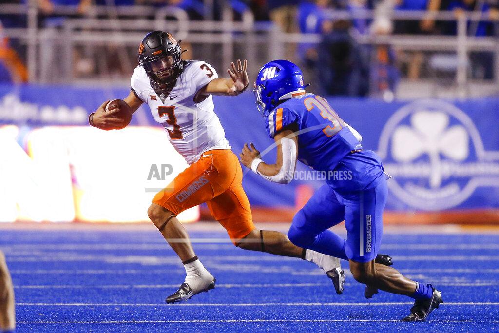 Steve Conner Oklahoma State quarterback Spencer Sanders (3) looks to fend off Boise State defensive end Isaiah Bagnah (30) during the second half of an NCAA college football game Saturday, Sept. 18, 2021, in Boise, Idaho. (AP Photo/Steve Conner)