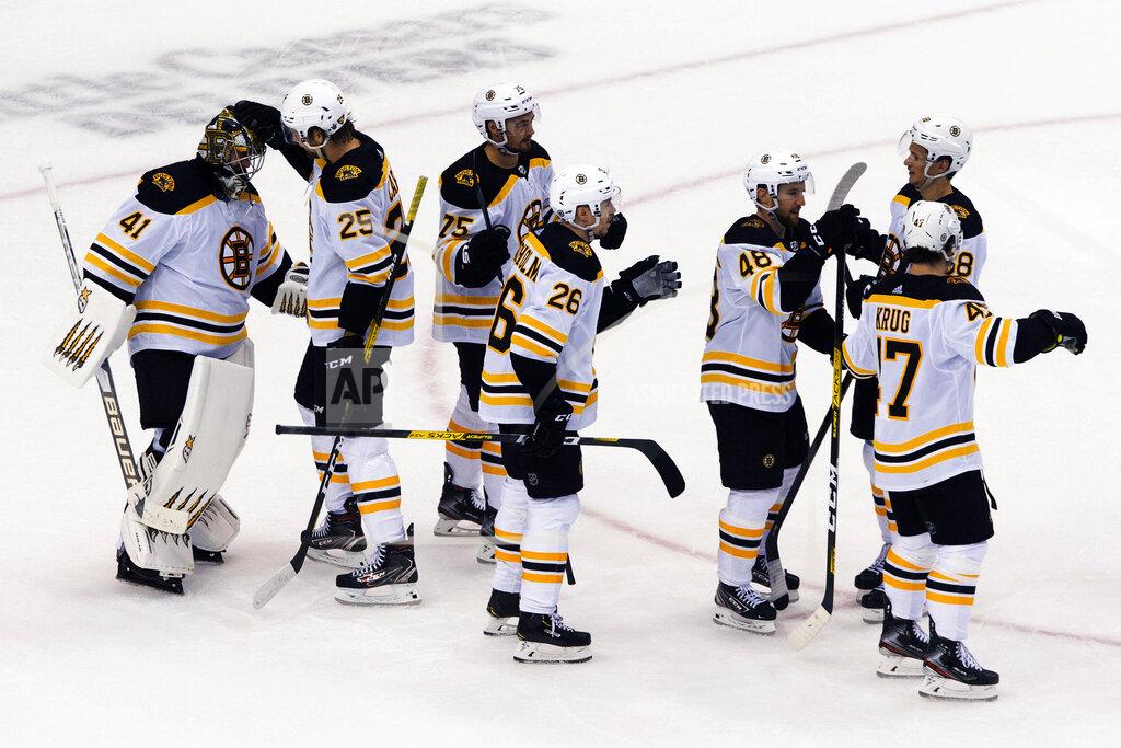 Chris Young Boston Bruins' Brandon Carlo (25) congratulates goaltender Jaroslav Halak as teammates celebrate their victory over the Carolina Hurricanes in NHL Eastern Conference Stanley Cup playoff game in Toronto on Saturday, Aug. 15, 2020. (Chris Young/The Canadian Press via AP)