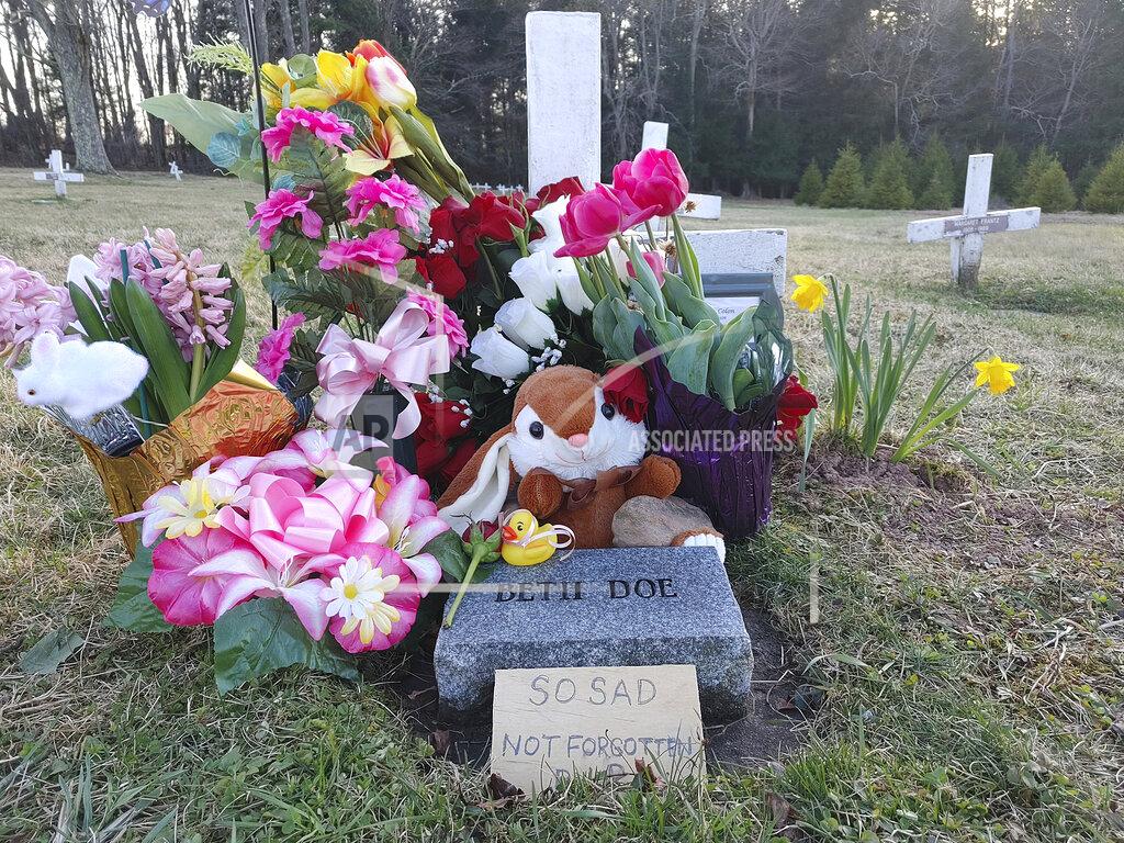 Kelly Monitz Phil Jeffries, retired funeral director and deputy coroner for Carbon County, Pa., placed a marker behind the flowers on the right, on Beth Doe and her baby’s grave with their true identities, Evelyn and Emily Grace Colon, after more than four decades, in Laurytown Road Cemetery in Lehigh Township, Pa., Sunday, April 4, 2021. Flowers and a child's toy also adorn the grave. Colon, who was known for decades here in Northeast Pennsylvania as Beth Doe, was brutally murdered and dumped off an Interstate 80 bridge in East Side borough in December 1976. (Kelly Monitz/Standard-Speaker via AP)