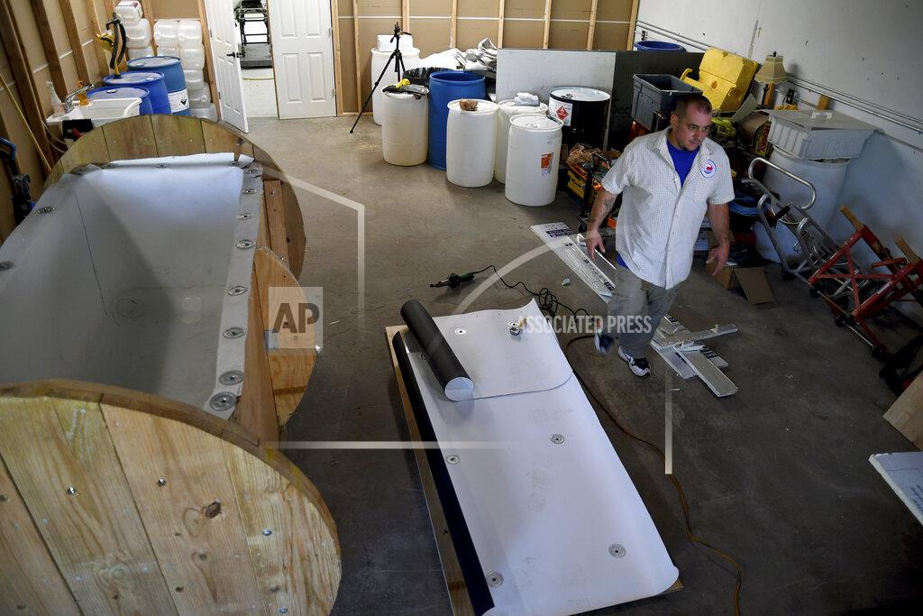 Thomas Peipert In this Wednesday, Aug. 11, 2021, photo, Chris Olachia walks past a nearly completed human body composting vessel in Arvada, Colo. On Sept. 7, Colorado became the second state after Washington to allow human body composting, and Oregon will allow the practice beginning next July. The vessel will be packed with wood chips and straw and will be able to compost a body in six months. About the size of a standard grave, the rectangular insulated wooden box is lined with waterproof roofing material and packed with wood chips and straw. Two large spool wheels on either end allow it to be rolled across the floor, providing the oxygenation, agitation and absorption required for a body to compost. (AP Photo/Thomas Peipert)