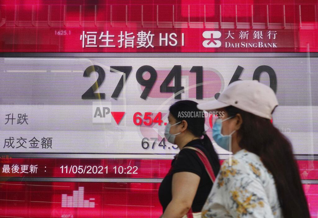 Vincent Yu People walk past a bank's electronic board showing the Hong Kong share index at Hong Kong Stock Exchange Tuesday, May 11, 2021. Shares dropped Tuesday in Asia after selling of several Big Tech companies pulled U.S. benchmarks lower. (AP Photo/Vincent Yu)