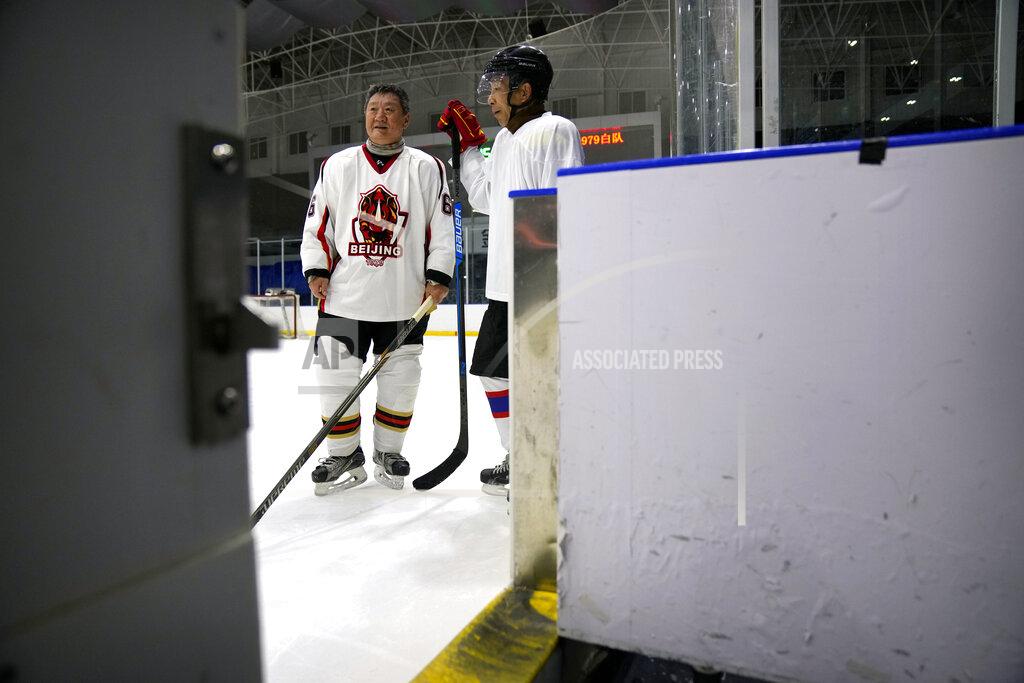 Mark Schiefelbein Members of the "1979" hockey club stand on the ice during a break between periods in a hockey match at a rink in Beijing, Wednesday, Jan. 12, 2022. Spurred by enthusiasm after China was awarded the 2022 Winter Olympics, the members of a 1970s-era youth hockey team, now around 60 years old, have reunited decades later to once again take to the ice. (AP Photo/Mark Schiefelbein)