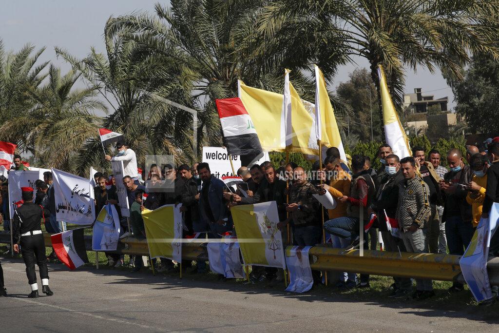 Andrew Medichini People stand by the road as they wait for Pope Francis, in Baghdad Iraq, Friday, March 5, 2021. Pope Francis heads to Iraq on Friday to urge the country's dwindling number of Christians to stay put and help rebuild the country after years of war and persecution, brushing aside the coronavirus pandemic and security concerns. (AP Photo/Andrew Medichini)