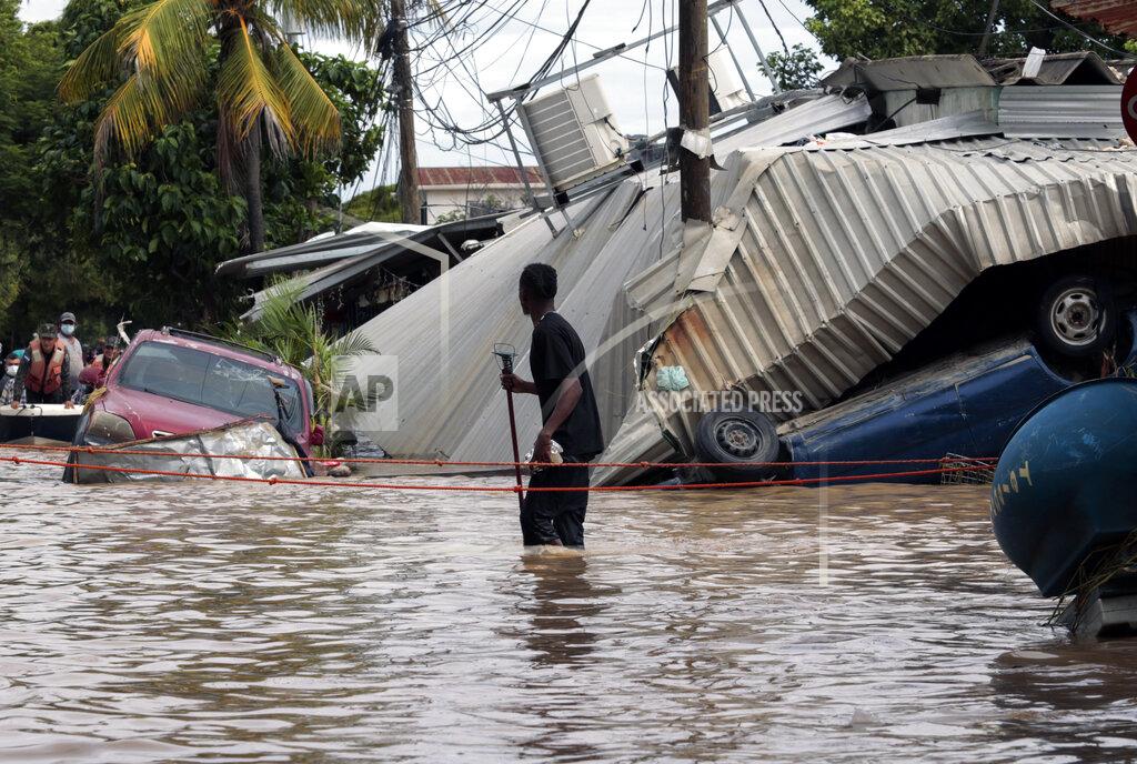 Delmer Martinez FILE - In this Nov. 6, 2020 file photo, a resident walking through a flooded street looks back at storm damage caused by Hurricane Eta in Planeta, Honduras. Flooded out Honduran and Guatemalan families stranded on rooftops in the most marginalized neighborhoods after the passage of hurricanes Eta and Iota portend a new wave of migration, observers across the region say. (AP Photo/Delmer Martinez, File)