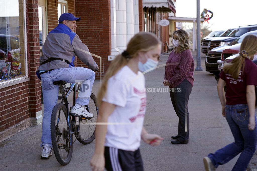 Charlie Riedel Tisha Coleman, public health administrator for Linn County, talks to a resident in front of her family hardware store in Mound City, Kan., Monday, Dec. 7, 2020. In late November, she spoke at a county commissioner's meeting to discuss a new mask mandate. It was her first day back in the office after her own bout with COVID-19. (AP Photo/Charlie Riedel)