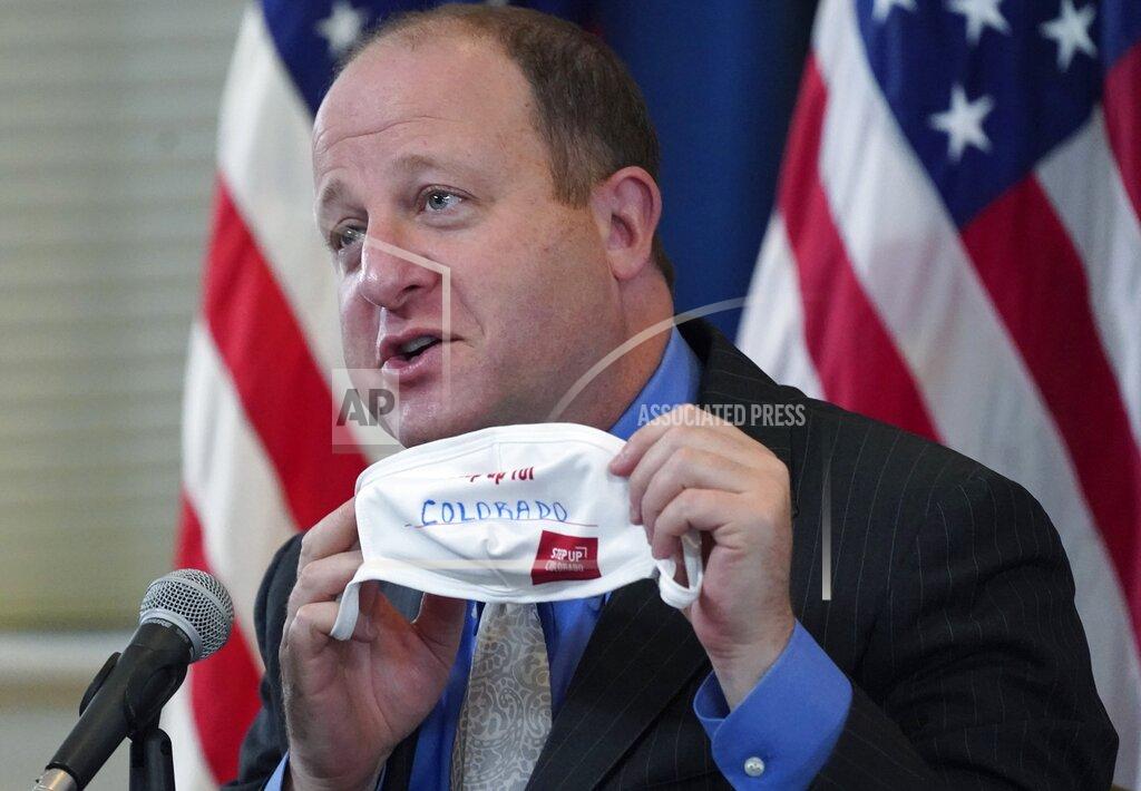 David Zalubowski FILE - In this Tuesday, Oct. 20, 2020, file photo, Colorado Gov. Jared Polis holds up a face mask featuring the state's new advertising campaign to encourage residents to protect against COVID-19 during a news conference about the steady increase in cases of the new coronavirus in the state in Denver. Colorado Gov. Polis is quarantining himself after learning that Aurora Mayor Mike Coffman tested positive for the coronavirus. Coffman's diagnosis on Sunday, Oct. 25, 2020, came over a week after he and the governor appeared with other officials at a news conference. A Polis spokesperson said the governor would quarantine while waiting to hear from contact tracers. Coffman said he worked from home starting Thursday after not feeling well and his symptoms were gone by Saturday. He says he got a rapid test Sunday in hopes of being cleared to return to his office and schedule but will now quarantine at home. (AP Photo/David Zalubowski, File)