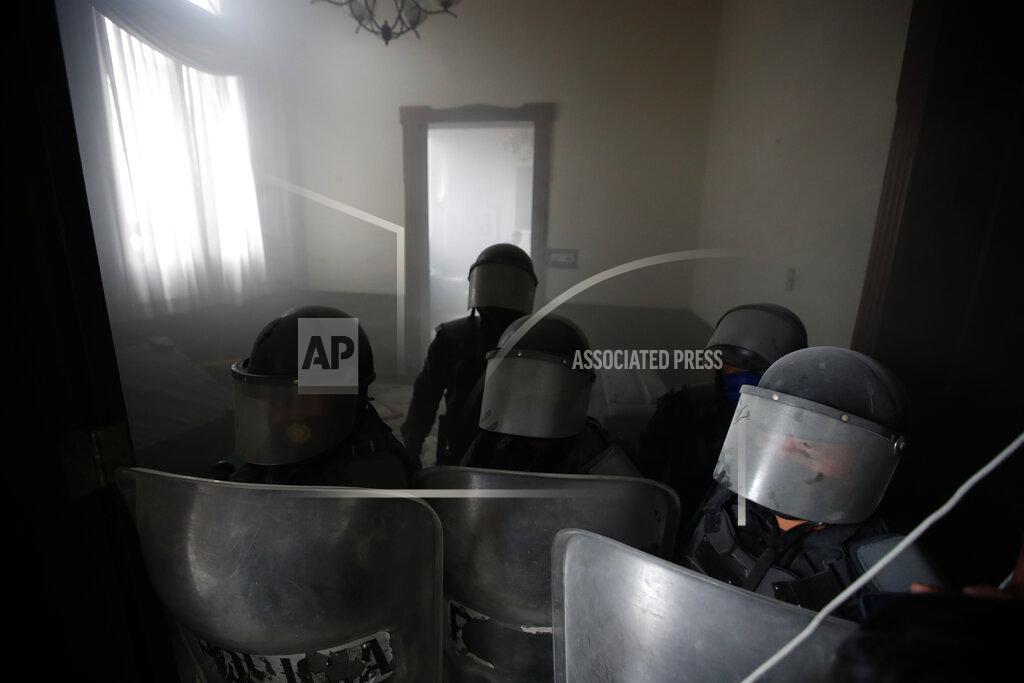 Moises Castillo Riot police secure the Congress building after protesters set part of the building on fire, in Guatemala City, Saturday, Nov. 21, 2020. Hundreds of protesters were protesting in various parts of the country Saturday against Guatemalan President Alejandro Giammattei and members of Congress for the approval of the 2021 budget that reduced funds for education, health and the fight for human rights. (AP Photo/Moises Castillo)