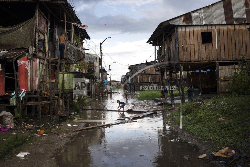Rodrigo Abd Children play in an inundated area of the Belen community in Iquitos, Peru, Saturday, March 20, 2021. Despite a scandal that shook the government in Peru's capital when over 480 government officials took advantage of their privileged positions to secretly receive early inoculations ahead of healthcare workers battling the new coronavirus pandemic, 66 people with connections in Iquitos jumped the queue this week to be vaccinated against COVID-19. (AP Photo/Rodrigo Abd)
