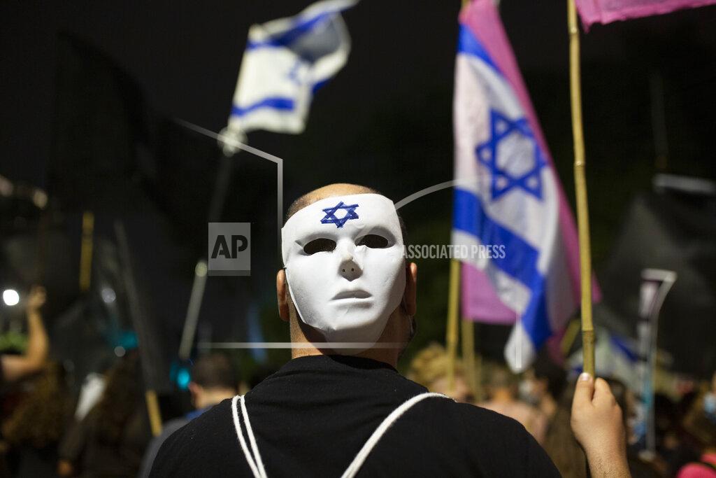 Maya Alleruzzo A man wears a mask at a protest outside of Israeli Prime Minister Benjamin Netanyahu's residence in Jerusalem, Saturday, Oct. 24, 2020. Weekly protests have been taking place for the past four months, with crowds calling on Netanyahu to resign over criminal corruption charges and his handling of the coronavirus. (AP Photo/Maya Alleruzzo)