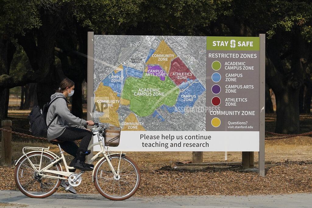 A bicyclist rides past a sign showing restricted zones around the Stanford University campus in Stanford, Calif., Wednesday, Sept. 2, 2020. With the coronavirus spreading through colleges at alarming rates, universities are scrambling to find quarantine locations in dormitory buildings and off-campus properties to isolate the thousands of students who have caught COVID-19 or been exposed to it. (AP Photo/Jeff Chiu)