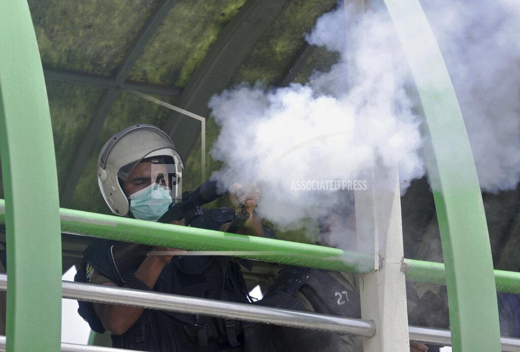 K.M. Chaudary A policeman fires tear gas to disperse supporters of Pakistan's key opposition party marching toward Islamabad, in Lahore, Pakistan, Wednesday, May 25, 2022. Pakistani authorities blocked off all major roads into the capital Islamabad on Wednesday, after a defiant former Prime Minister Imran Khan said he would march with demonstrators to the city center for a rally he hopes will bring down the government and force early elections. (AP Photo/K.M. Chaudary)