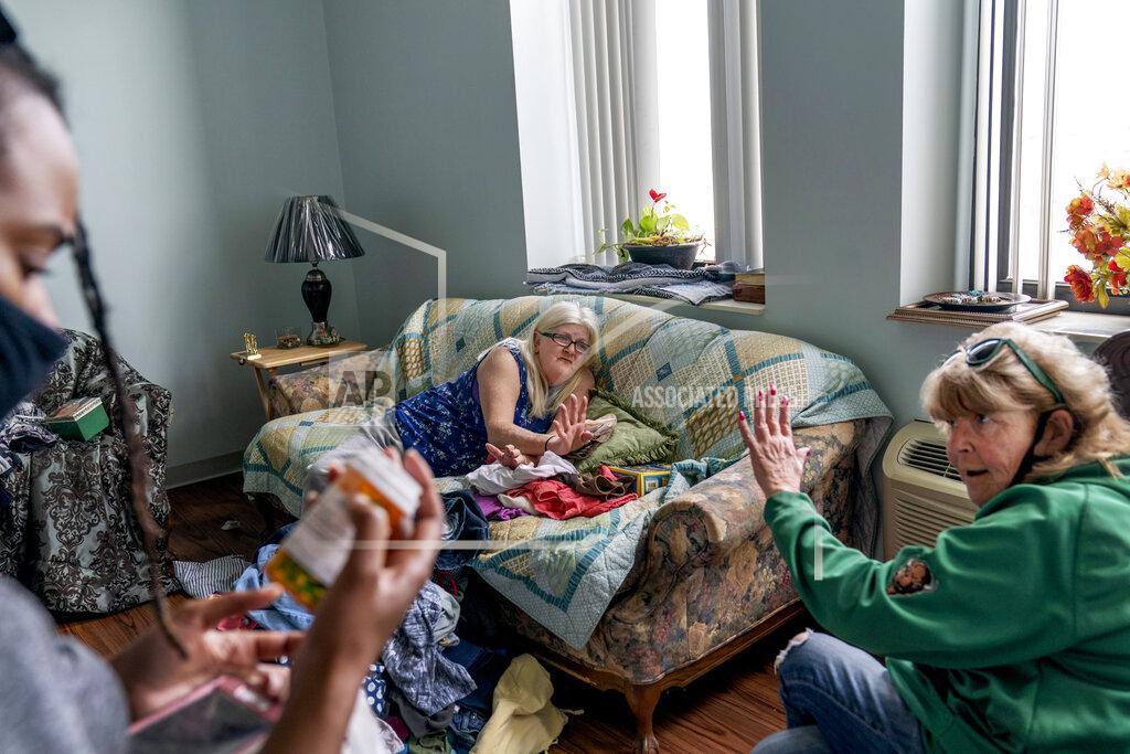 David Goldman Sue Howland, right, and Larrecsa Cox, left, members of the Quick Response Team whose mission is to save every citizen who survives an overdose from the next one, help Betty Thompson, 65, who struggles with alcohol addiction, count her medications at her apartment in Huntington, W.Va., Wednesday, March 17, 2021. Thompson called that morning to say she needed help. With preexisting conditions that make her especially vulnerable to COVID, she'd been terrified she'd get the virus and die, and so she's drank more these months than she ever has before. (AP Photo/David Goldman)