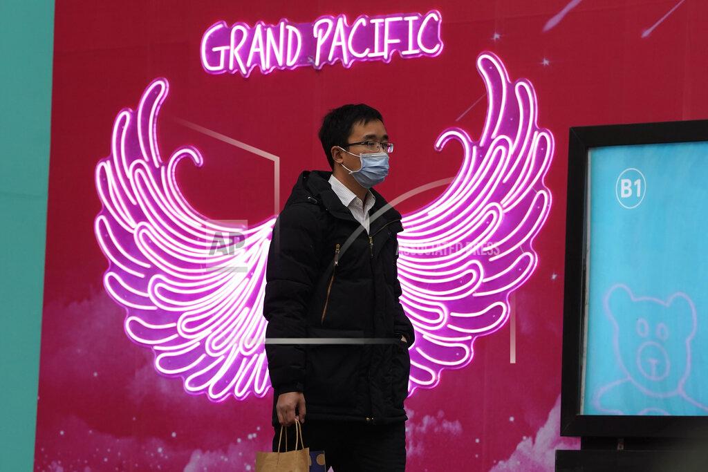 Ng Han Guan A man wearing a mask to protect from the coronavirus passes by neon lights along a retail street in Beijing Tuesday, March 2, 2021. The state of the world's second largest economy takes precedence among the myriad issues presented by Premier Li Keqiang in his address at the National People's Congress opening session to take place on Friday, March 5. 2021. (AP Photo/Ng Han Guan)