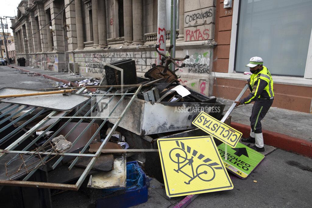 Moises Castillo A traffic officer removes debris from the front of the Congress building that was damaged during protests in Guatemala City, Sunday, Nov. 22, 2020. Protesters broke into the building and set it partially on fire amid growing demonstrations against President Alejandro Giammattei and the legislature for approving a controversial budget that cut educational and health spending. (AP Photo/Moises Castillo)