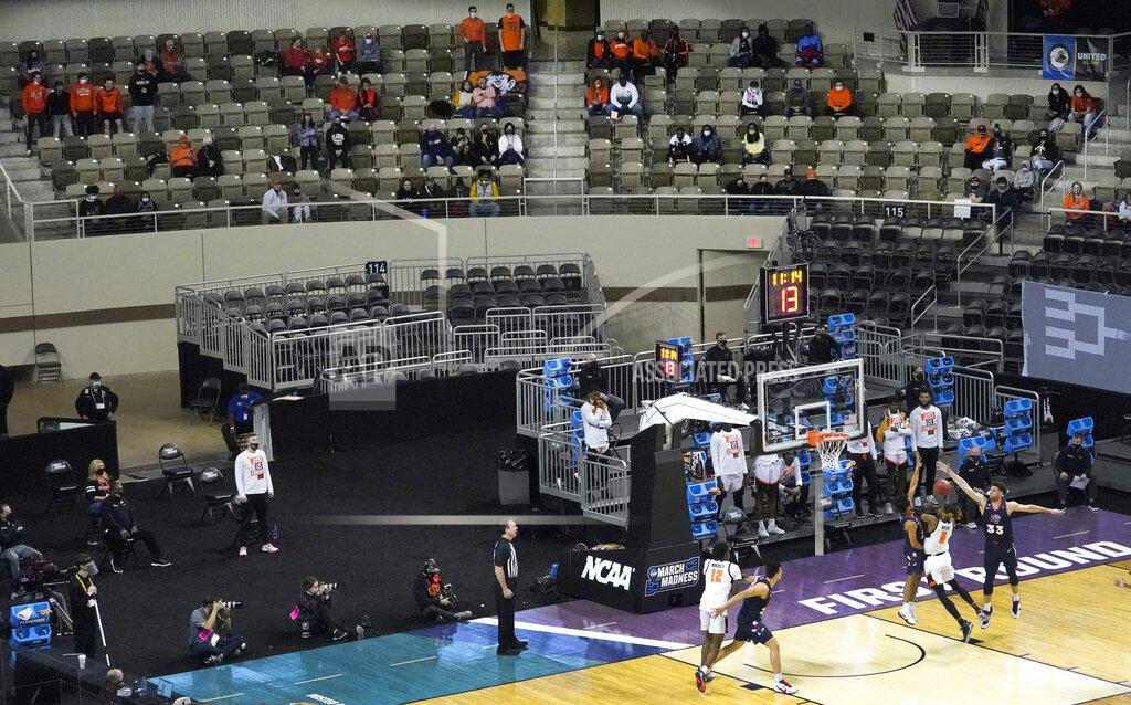 Charles Rex Arbogast A limited number of fans watch a first round NCAA college basketball tournament game Friday, March 19, 2021, between Oklahoma State and Liberty at the Indiana Farmers Coliseum in Indianapolis. No bands. No cheer squad. No buildings filled with neutral fans suddenly throwing their support behind a plucky double-digit underdog hoping to pull off an upset. This is a decidedly different NCAA tournament experience for players and coaches when they get on the court. (AP Photo/Charles Rex Arbogast)