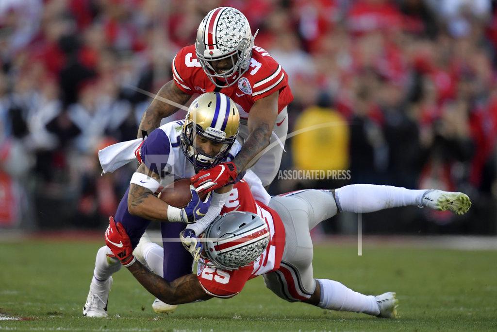 Mark J. Terrill Washington wide receiver Andre Baccellia, middle, is tackled by Ohio State cornerback Damon Arnette top, and safety Brendon White during the first half of the Rose Bowl NCAA college football game Tuesday, Jan. 1, 2019, in Pasadena, Calif. (AP Photo/Mark J. Terrill)