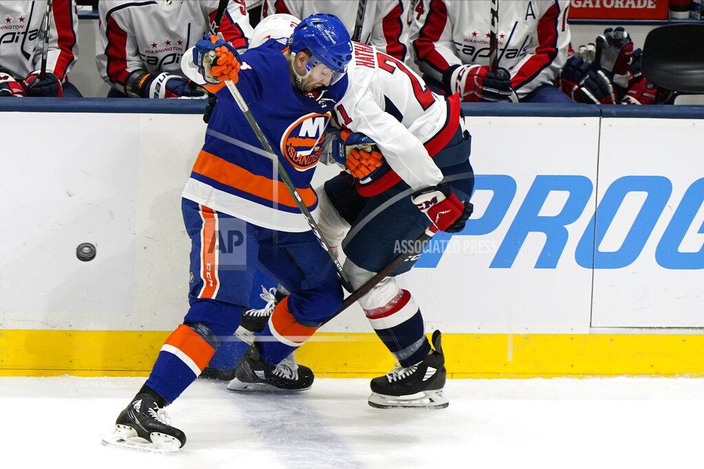 Kathy Willens New York Islanders defenseman Adam Pelech (3) checks Washington Capitals right wing Garnet Hathaway (21) against the boards during the first period of an NHL hockey game Thursday, April 22, 2021, in Uniondale, N.Y. (AP Photo/Kathy Willens)