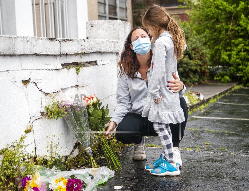 Alyssa Pointer Mallory Rahman and her daughter Zara place flowers near a makeshift memorial outside of the Gold Spa in Atlanta, Wednesday, March 17, 2021. Police in the Atlanta suburb of Gwinnett County say they've begun extra patrols in and around Asian businesses there following the shooting at three massage parlors in the area that killed eight, most of them women of Asian descent. (Alyssa Pointer/Atlanta Journal-Constitution via AP)
