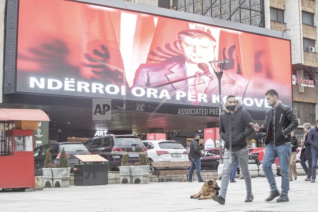 Visar Kryeziu People walk past a giant LED monitor showing electoral material of the resigned president Hashim Thaci in capital Pristina, Kosovo, on Wednesday, Feb. 10, 2021. Kosovo holds an early general election on upcoming Sunday Feb. 14, amid the coronavirus pandemic, economic downturn and stalled negotiations with wartime foe Serbia. (AP Photo/Visar Kryeziu)