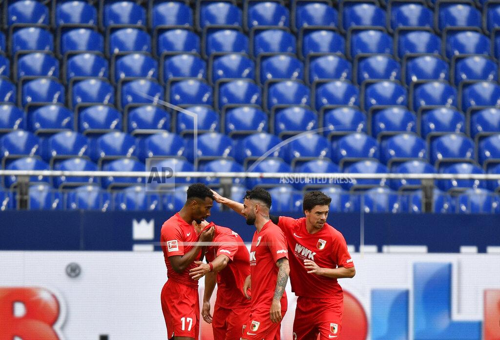 Martin Meissner Augsburg's Noah Saranren Bazee, left, celebrates with teammates after scoring his side's second goal during the German Bundesliga soccer match between FC Schalke 04 and FC Augsburg at the Veltins-Arena in Gelsenkirchen, Germany, Sunday, May 24, 2020. The German Bundesliga becomes the world's first major soccer league to resume after a two-month suspension because of the coronavirus pandemic. (AP Photo/Martin Meissner, Pool)