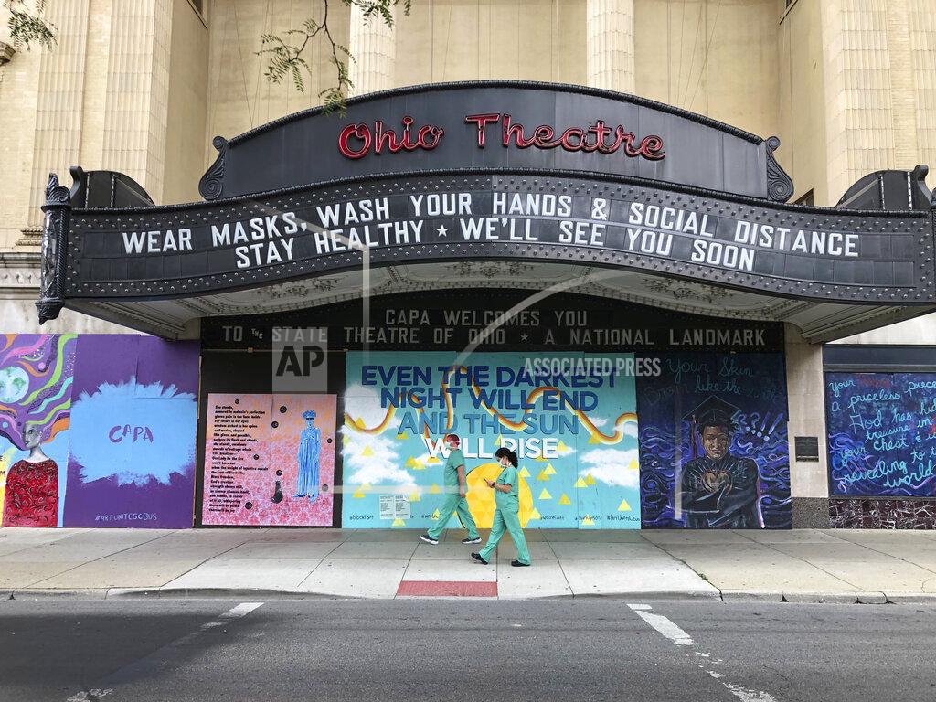 Julie Carr Smyth FILE — In this Aug. 26, 2020 file photo, workers in scrubs and masks walk by the Ohio Theatre in Columbus, Ohio, amid the coronavirus pandemic. (AP Photo/Julie Carr Smyth, File)