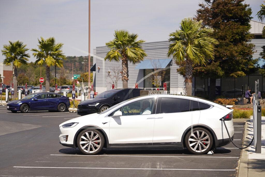 Eric Risberg A man talks on his phone while sitting in his electric car at a Tesla charging station Friday, April 2, 2021, Marin City, Calif. The president and auto industry maintain the nation is on the cusp of a gigantic shift to electric vehicles and away from liquid-fueled cars, but biofuels producers and some of their supporters in Congress aren't buying it and argue now is the time to increase sales of ethanol and biodiesel, not abandon them. (AP Photo/Eric Risberg)