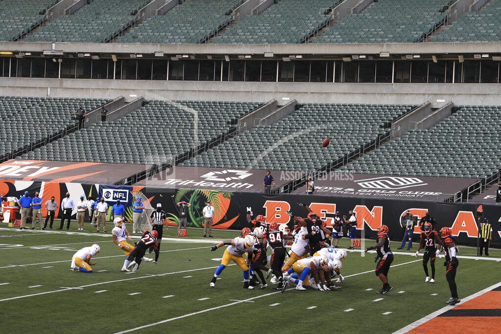 Aaron Doster FILE—In this file photo from Sept. 13, 2020, Los Angeles Chargers kicker Mike Badgley (4) boots a field goal out of the hold of Ty Long (1) at Paul Brown stadium that is devoid of fans during the second half of an NFL football game against the Cincinnati Bengals, in Cincinnati. About one in six Ohio school districts asked the state for permission to add additional spectators for fall sporting events, exceeding the limits set by Gov. Mike DeWine in last month's sports order, records show. (AP Photo/Aaron Doster, File)