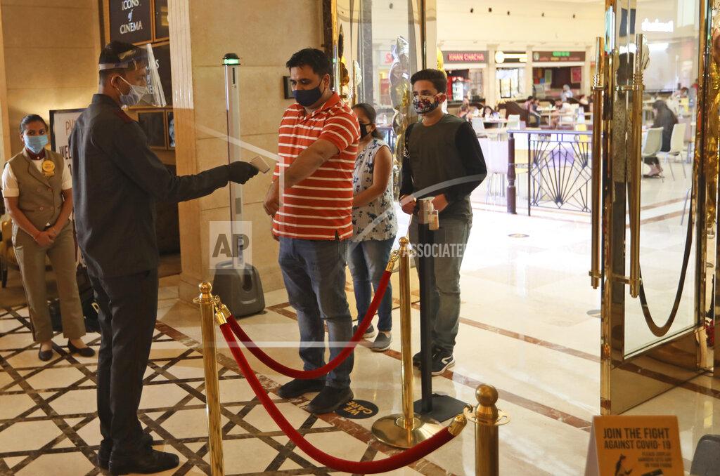 Manish Swarup An employee checks the temperature of COVID-19 warriors and their families arriving as cinemas reopen with a special screening for them at the PVR movie theater in New Delhi, India, Thursday, Oct. 15, 2020. Seven months after screens went dark, cinemas reopened Thursday in much of India with mostly old titles on the marquee — a sign of the country’s efforts to return to normal as the pace of coronavirus infections slows but also of the roadblocks that remain. (AP Photo/Manish Swarup)