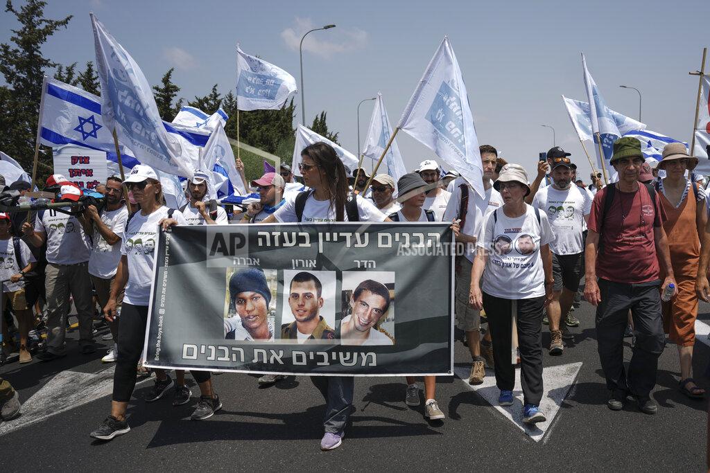 Ariel Schalit Supporters and family members of Israeli soldiers Hadar Goldin and Oron Shaul who were killed during the 2014 war in the Gaza Strip and captive Israeli civilian Avera Mengistu, march and calling for the return of their remains and the return of Mengistu and other Israelis held in Gaza back to Israel, near Kibbutz Yad Mordechai close to the Israeli Gaza border, Friday, Aug. 5, 2022. Hebrew on banner reads, "The boys are still in Gaza" and " bringing back the boys". (AP Photo/Ariel Schalit)