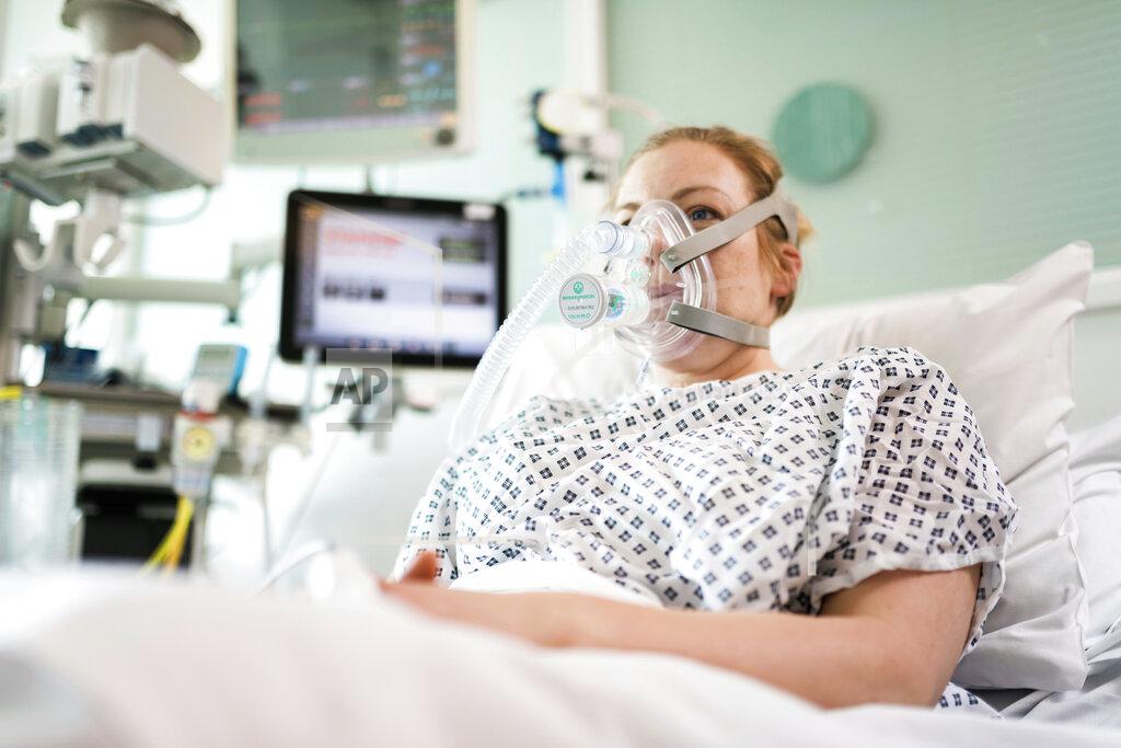 James Tye In this Friday, March 27, 2020 photo provided by UCLH a female volunteer demonstrates the use of a CPAP device at UCL Hospital in London. Formula One team Mercedes has helped to develop a breathing aid that could keep coronavirus patients out of intensive care and ease some pressure on Britain’s strained health service. Mercedes worked with engineers at the University College London and clinicians at University College London Hospital in a combined effort involving seven Britain-based teams to adapt and improve a device that bridges the gap between an oxygen mask and the need for full ventilation. (UCLH via AP)