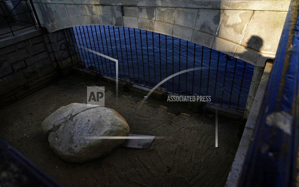 A visitor casts a shadow while looking at Plymouth Rock, the traditional point of arrival of the Pilgrims on the Mayflower in 1620, in Plymouth, Mass., Wednesday, Aug. 12, 2020. Disease introduced by traders and settlers, either by happenstance or intention, played an important role in the conquest of Native peoples. And that inconvenient fact, well known to the Natives' descendants, is contrary to the traditional narrative of the "New World." (AP Photo/David Goldman)