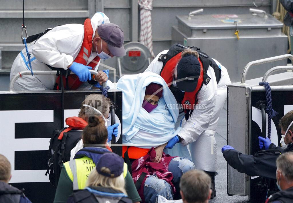 Gareth Fuller A woman is helped by Border Force officers as a group of people thought to be migrants are brought in to Dover, onboard a Border Force vessel, following a small boat incident in the Channel, in Kent, England, Monday July 26, 2021. (Gareth Fuller/PA via AP)